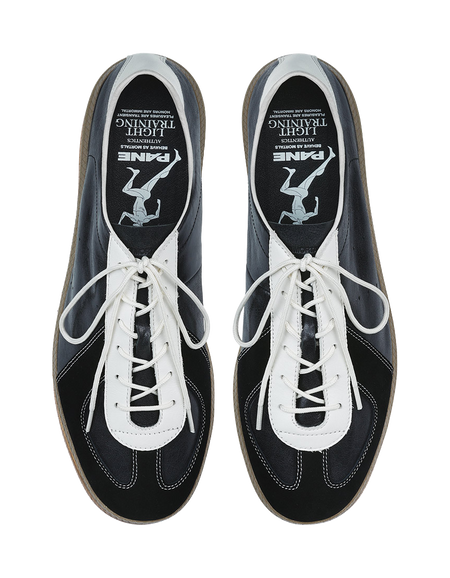 Front view of black low-top sneakers with white laces and white stitching