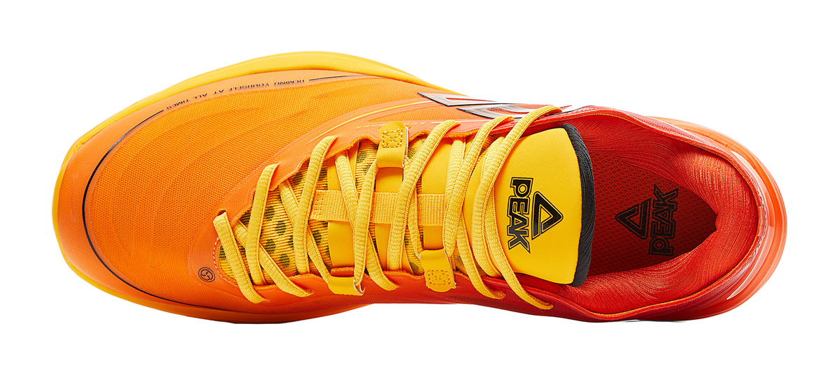 Basketball shoe with orange upper, yellow laces, and black triangular heel logo