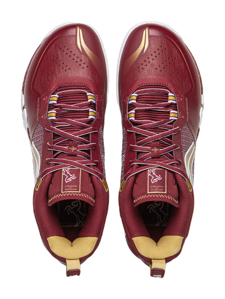 Red lace-up badminton shoe with textured toe perforations and cushioned collar.