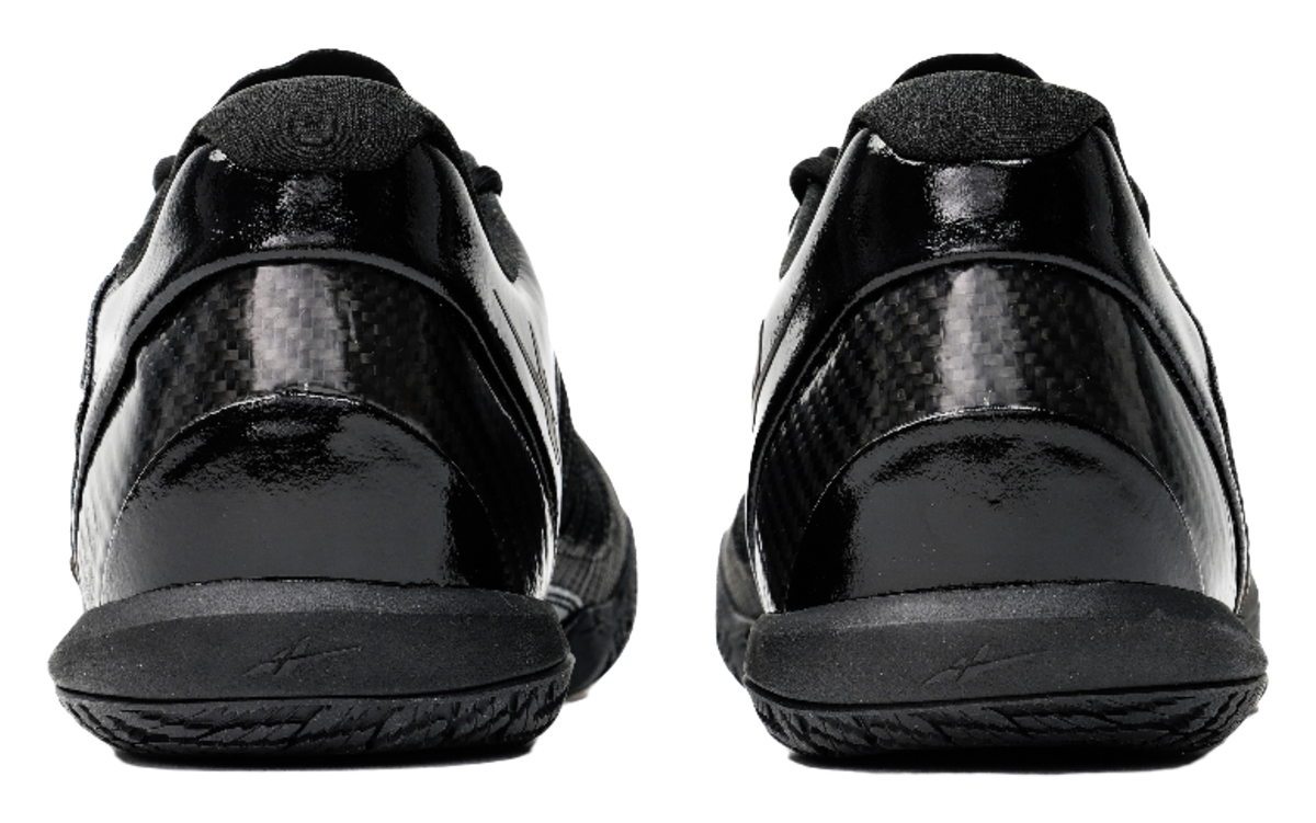 Black low-top basketball shoes, rear view with cushioned heel and lace collar.