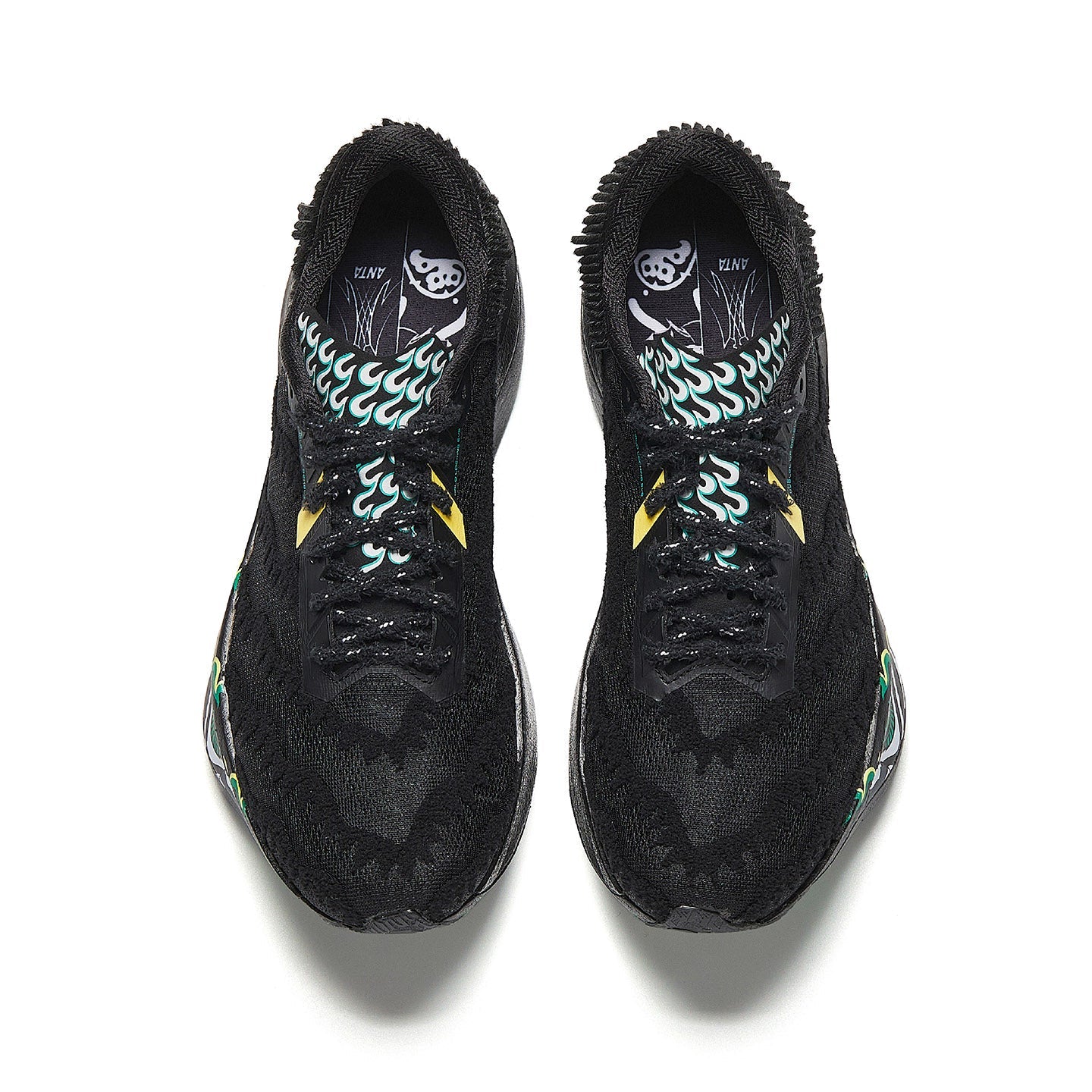 Pair of black running shoes with patterned inner lining and green flame graphics.