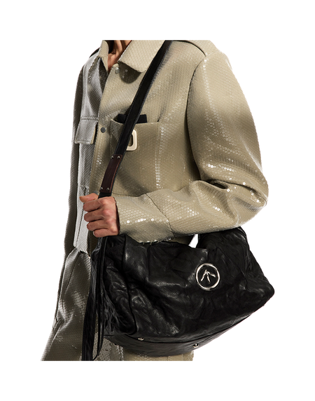 Black pleated leather crossbody bag with flap, logo emblem, and shoulder strap.