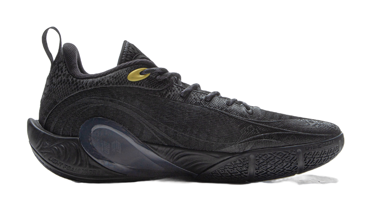 Black low-top basketball shoe with textured upper and gold logo accents