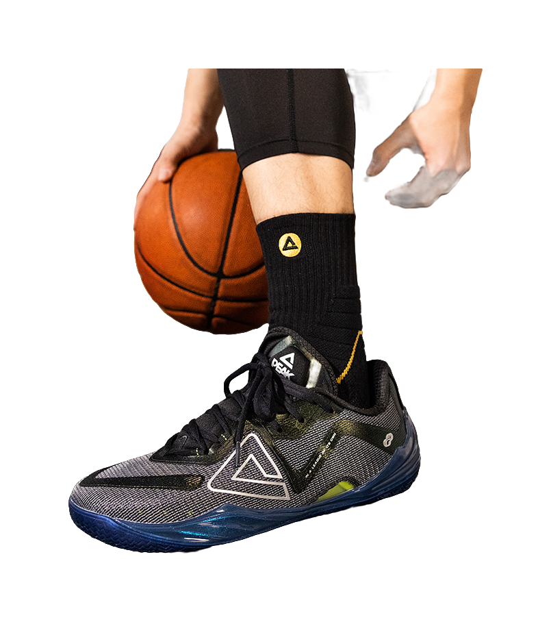 Basketball shoe on foot, black socks and lace-up upper with teal accents and blue sole