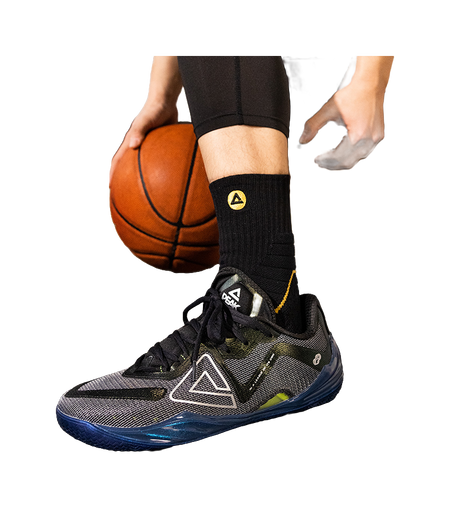 Basketball shoe on foot, black socks and lace-up upper with teal accents and blue sole