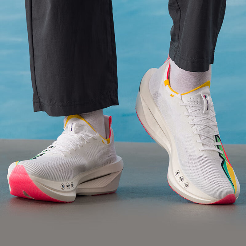 Pair of Xtep marathon racing shoes on feet, white uppers with multicolor panels and red soles.