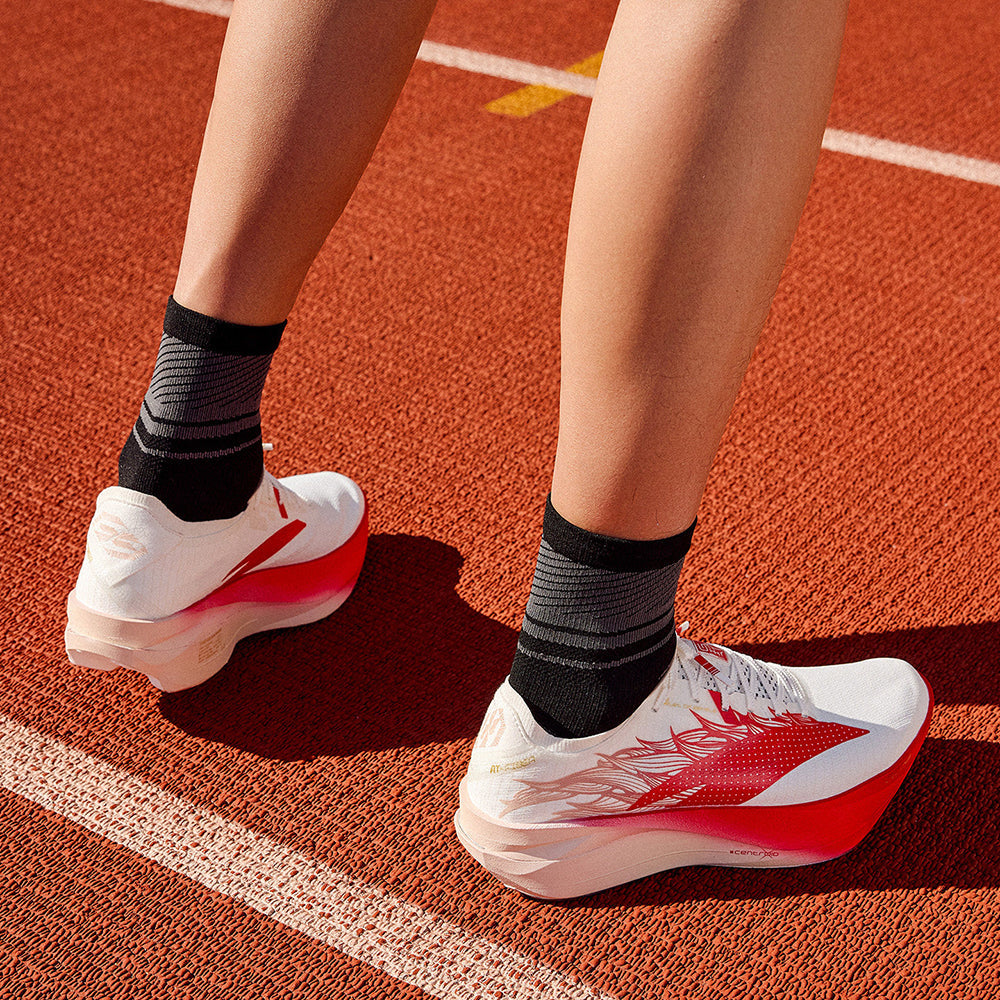 White and red running shoes with horse design, worn with black socks