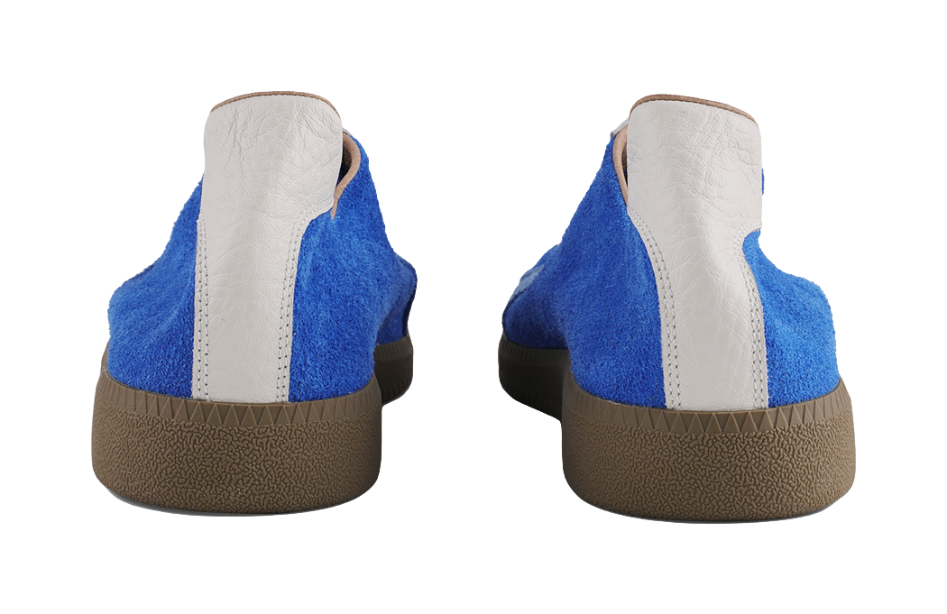 Heel view of blue low-top trainers with white back panels and brown outsole.