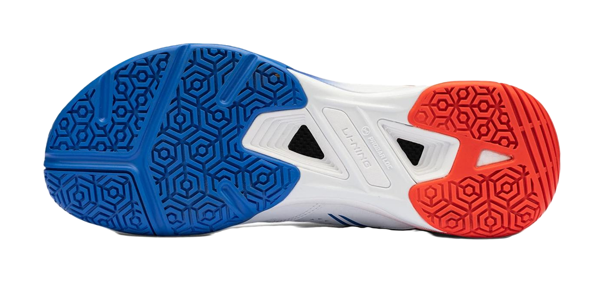 Badminton shoe outsole in blue and red with hex tread and center vent grips