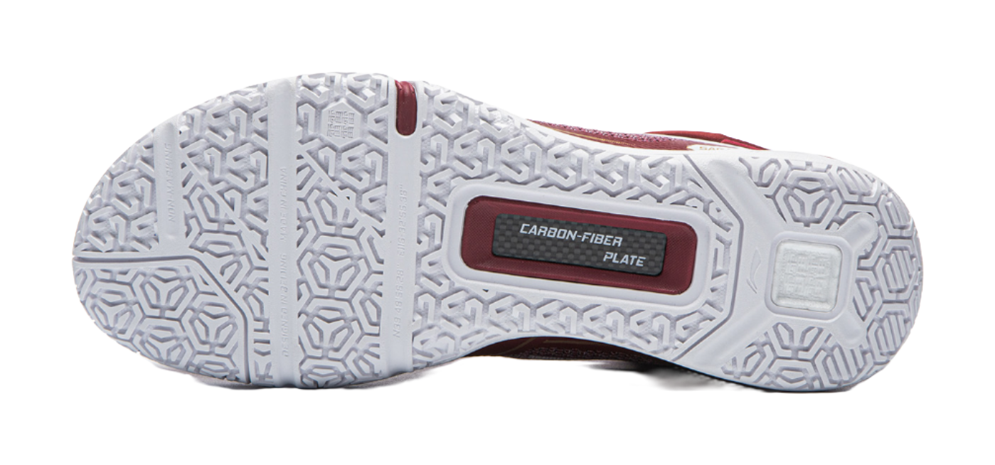 White outsole of red badminton shoe with hex tread pattern and CARBON-FIBER plate.