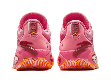 Pink low basketball shoes with rear tabs, lace loops, and orange patterned outsole