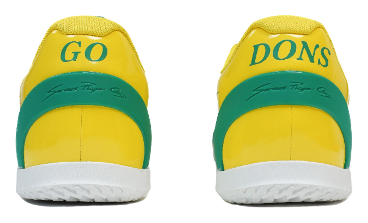 Rear view of yellow basketball shoes with green heel tabs marked "Go Dons"