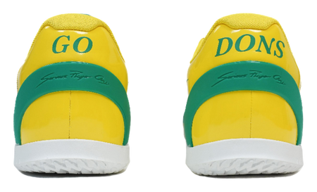 Rear view of yellow basketball shoes with green heel tabs marked "Go Dons"