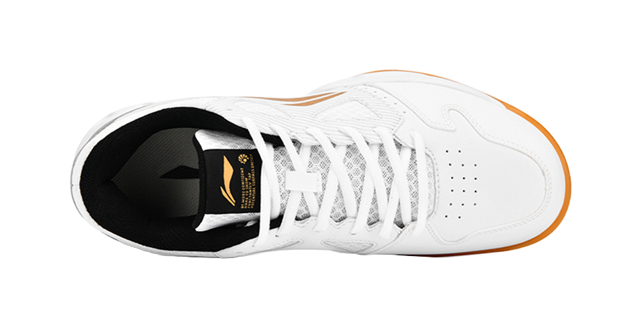 White badminton shoe toe and laces with black collar and gold emblem on inner tongue