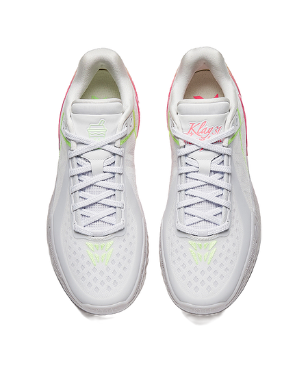 Pair of white basketball shoes with lace-up fronts and green logo accents