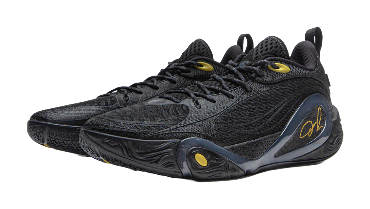 Black low-top basketball shoe with oval side detail and gold signature logo