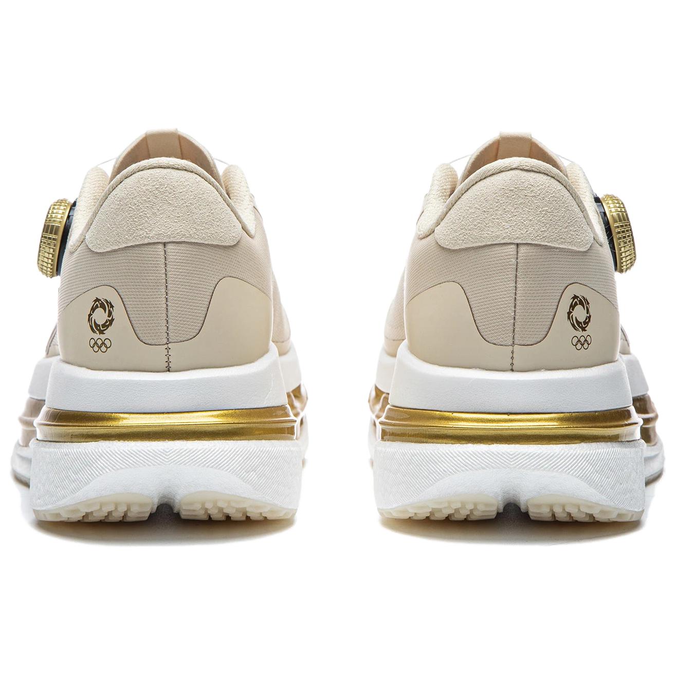 Women’s running shoes heel view in light beige with gold emblem and cushioned sole.