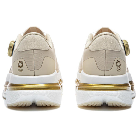 Women’s running shoes heel view in light beige with gold emblem and cushioned sole.