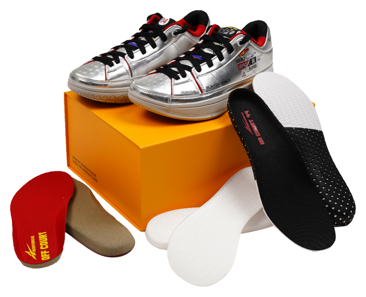 Silver basketball shoes with black and red socks, shown on an orange box