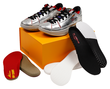 Silver basketball shoes with black and red socks, shown on an orange box