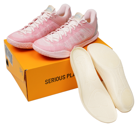 Pink basketball shoes with matching insoles, resting on an orange logo box