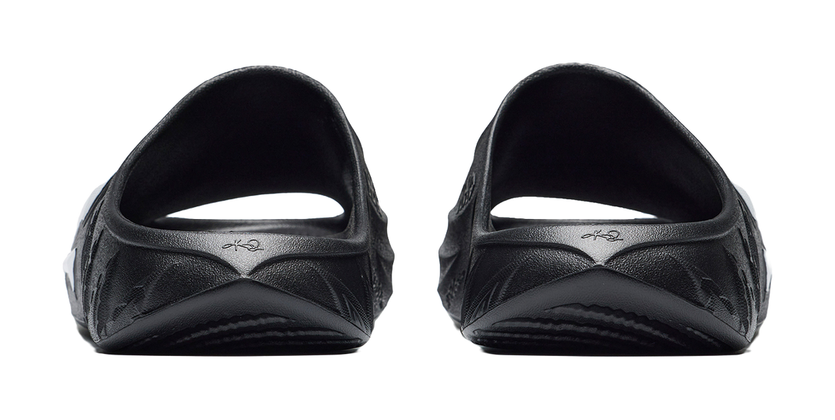 Men's black slide slippers, heel view with molded cushioning and subtle brand marks