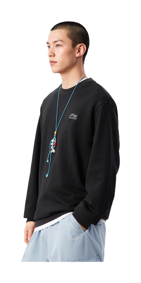 Black crewneck sweatshirt worn by model, side view; ribbed cuffs and hem, chest logo.