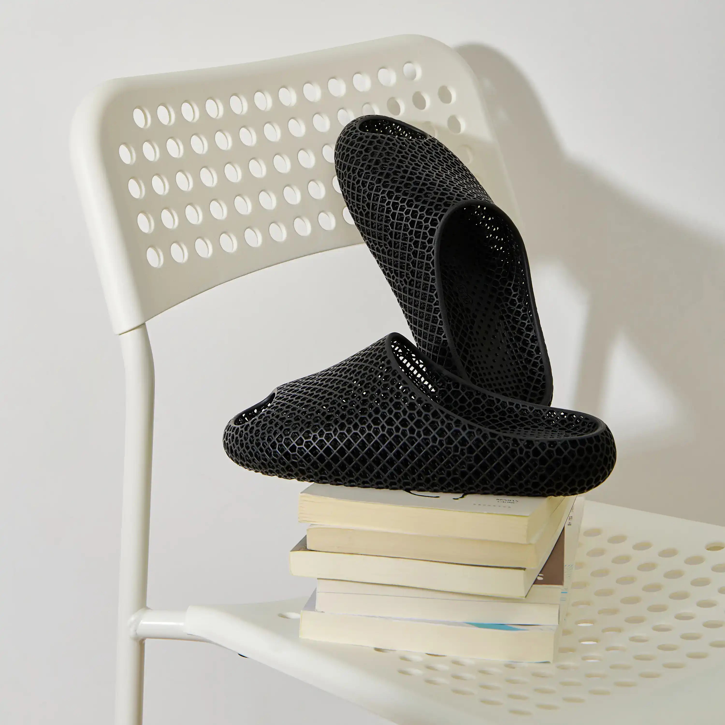 3D printed slippers, black pair with textured surface on a white chair