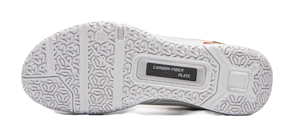 Outsole of white badminton shoe with textured grip pattern and carbon fiber plate label