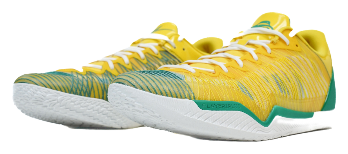 Pair of yellow basketball shoes with green accents and white textured outsoles