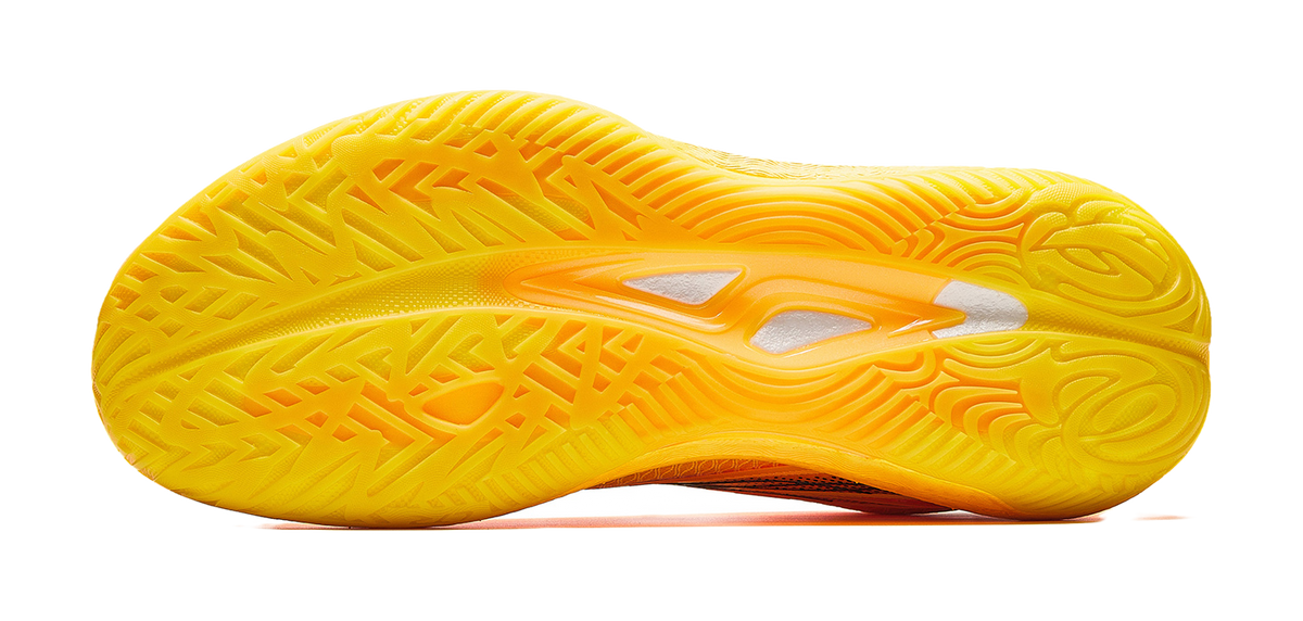 Yellow basketball shoe outsole with patterned tread and orange midfoot graphic