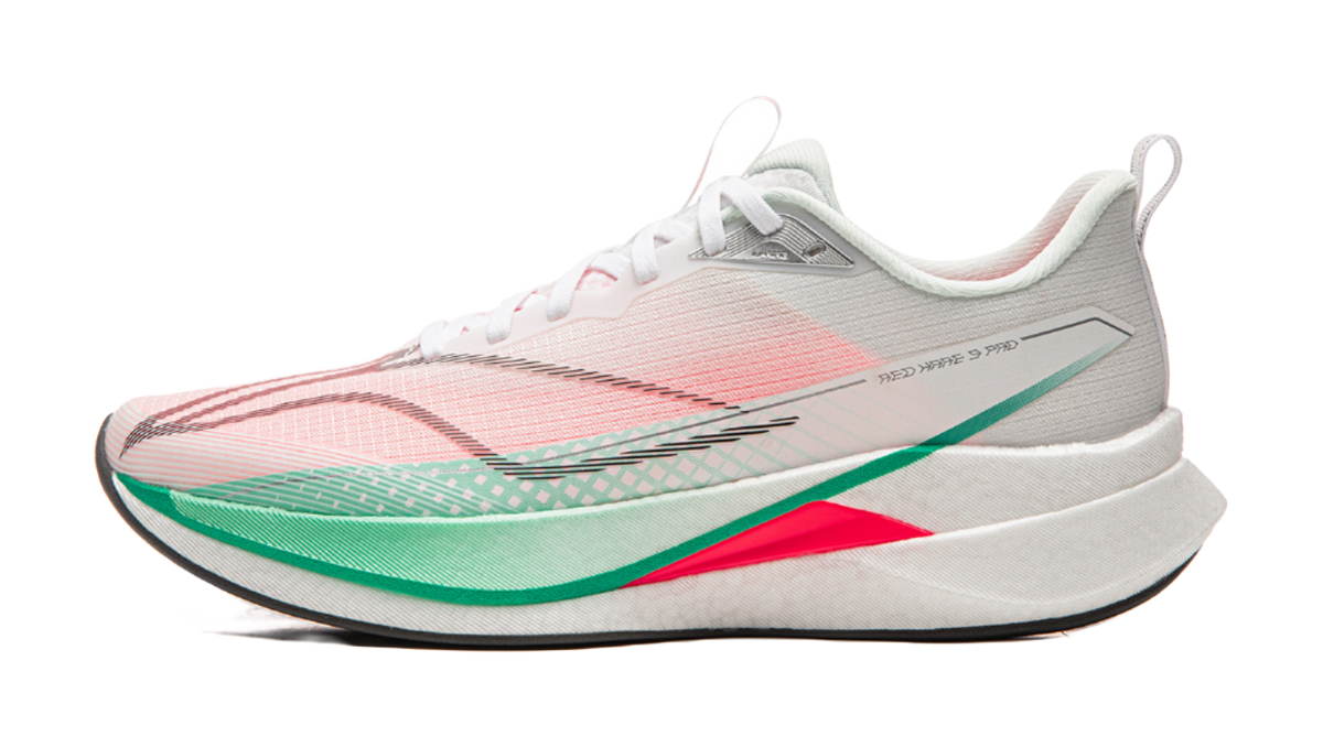 Running shoe with white base and pink patterned upper, green stripe trim, red accent on midsole