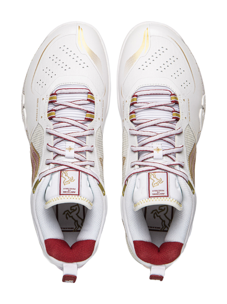 Pair of white badminton shoes with red laces, perforations, and padded tongue