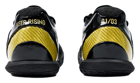Black low-cut basketball shoes with yellow mesh panels and heel text detail