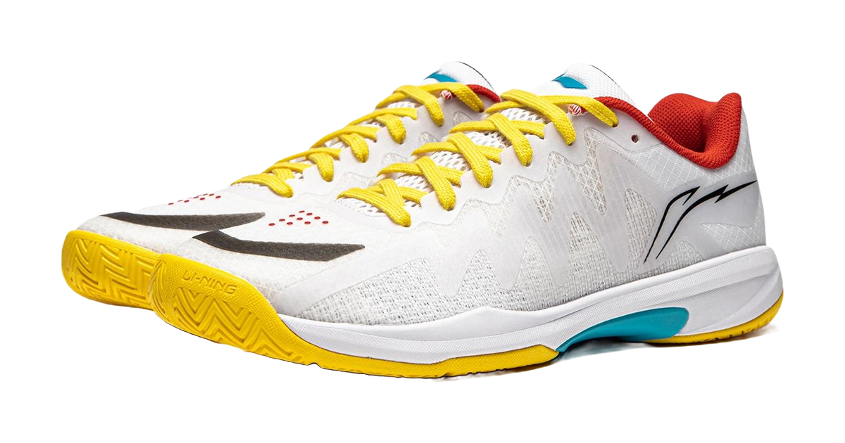 White table tennis shoe with yellow laces and yellow outsole, black logo and red collar