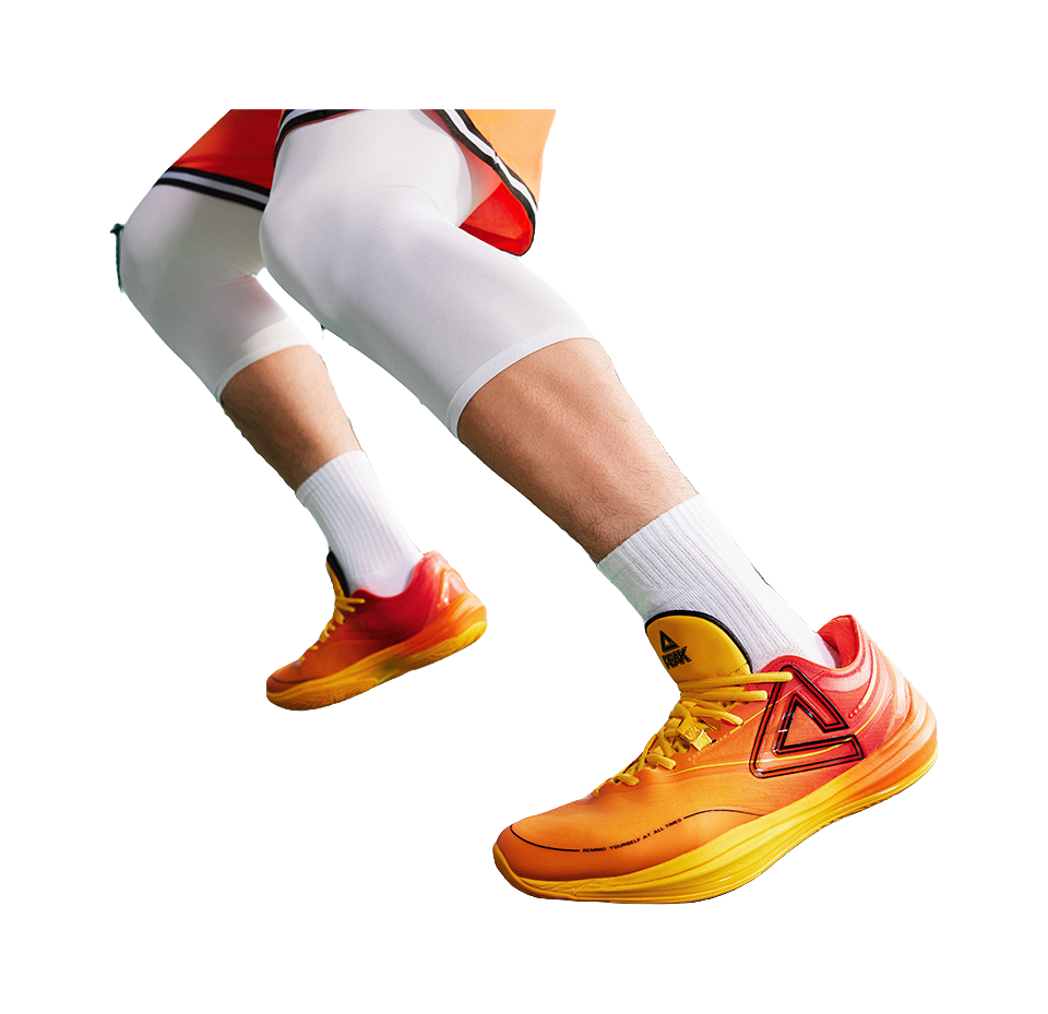 Basketball shoe on foot with orange/yellow upper and red heel collar logo