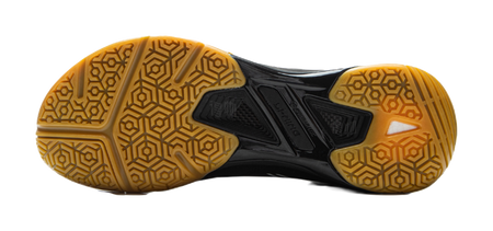Black outsole of badminton shoe with gold hex traction pattern and molded center pods.