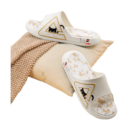 White slide sandal resting on fabric, with triangular cat graphic on the strap