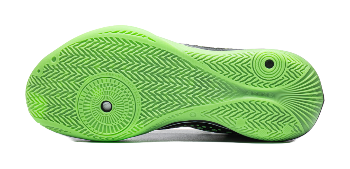 Underside sole of black and neon green low basketball shoe with green traction tread pattern