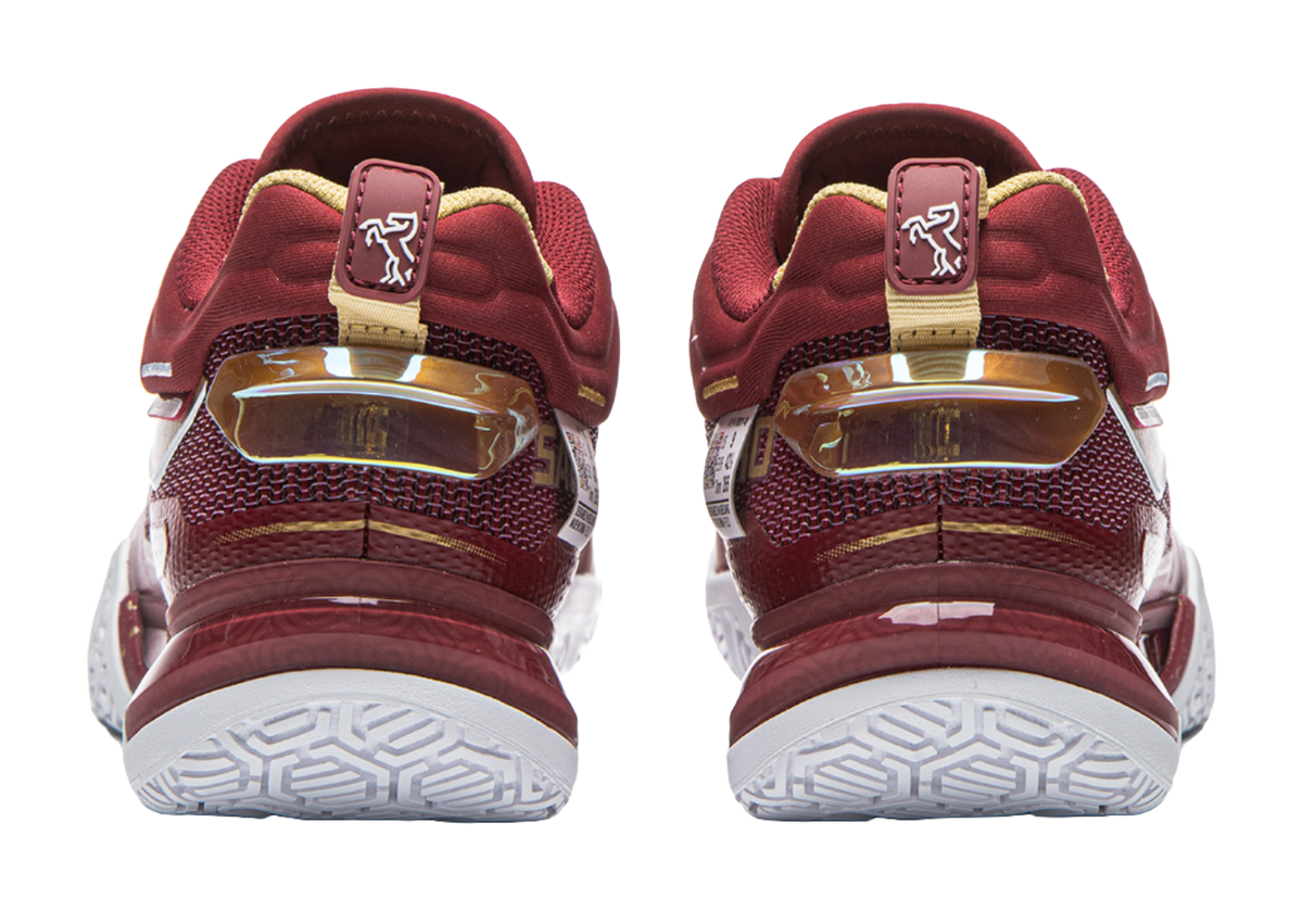 Red badminton shoe back view with strap tab, heel cushioning, and white tread outsole.