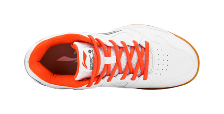White low-top badminton shoe with orange lining, orange laces, and perforated toe