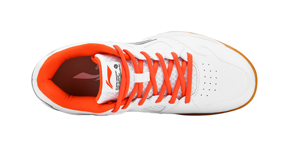 White low-top badminton shoe with orange lining, orange laces, and perforated toe