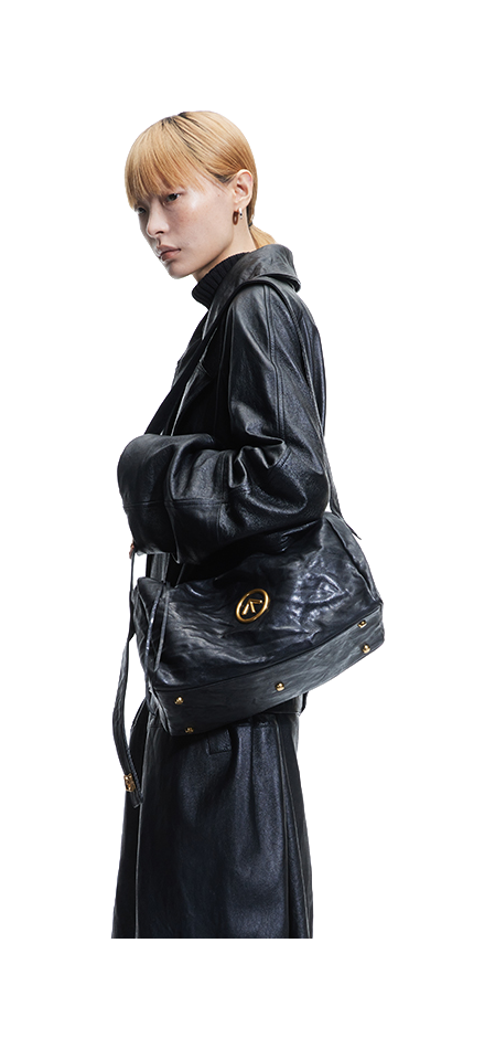 Black pleated leather crossbody bag with front emblem and adjustable strap.