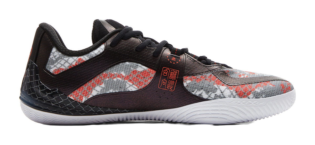 Side view basketball shoe with speckled upper, black overlays, red accents