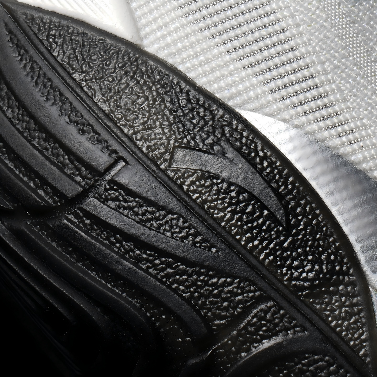 Black basketball shoe insole-side outsole detail with textured tread and curved channels