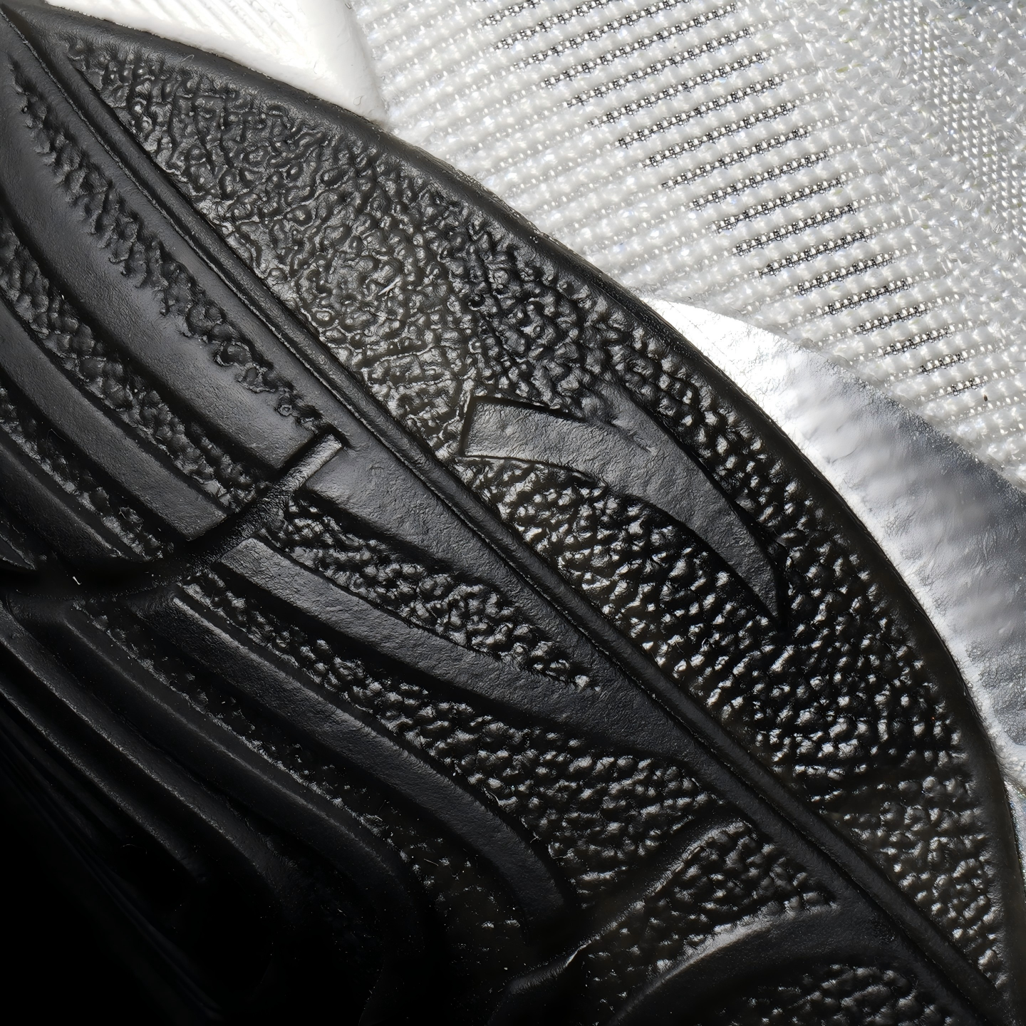 Black basketball shoe insole-side outsole detail with textured tread and curved channels