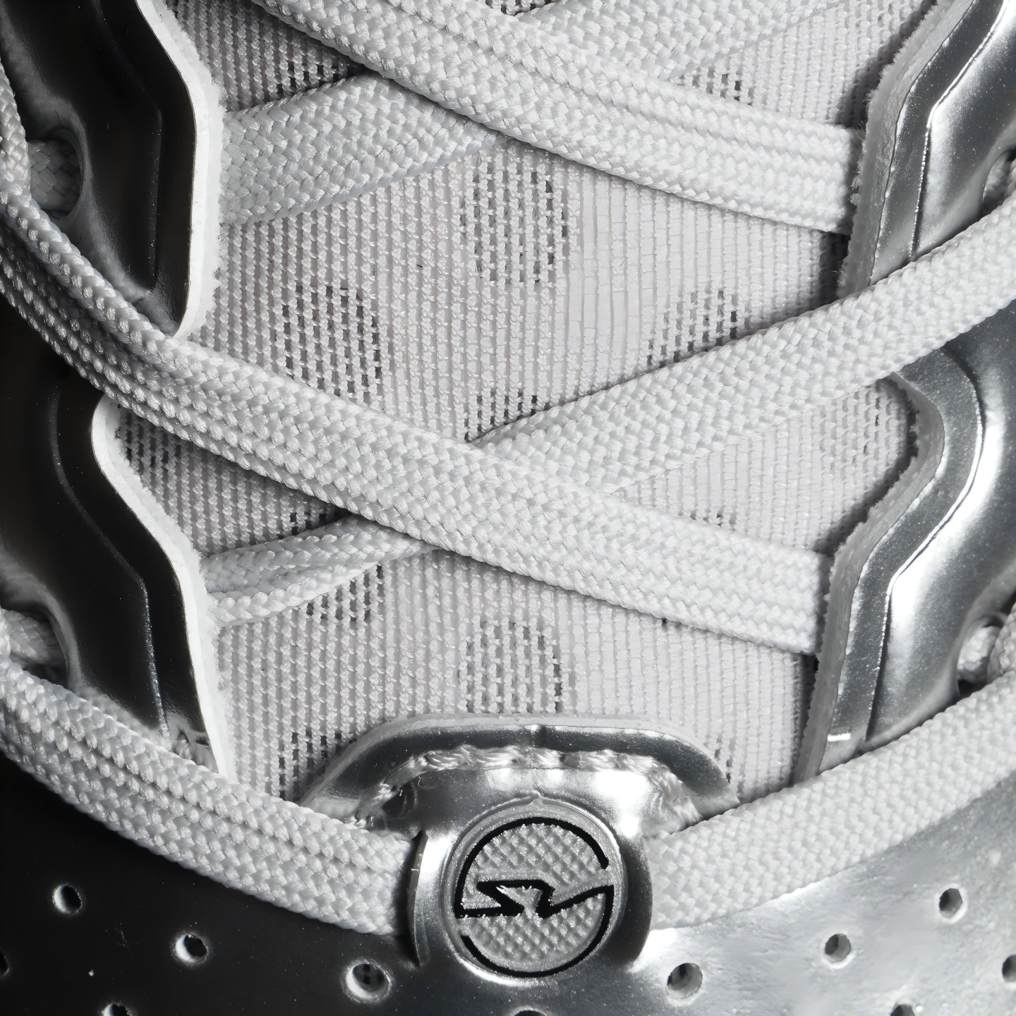 Silver sneaker lace panel with woven texture and round logo patch at the ankle