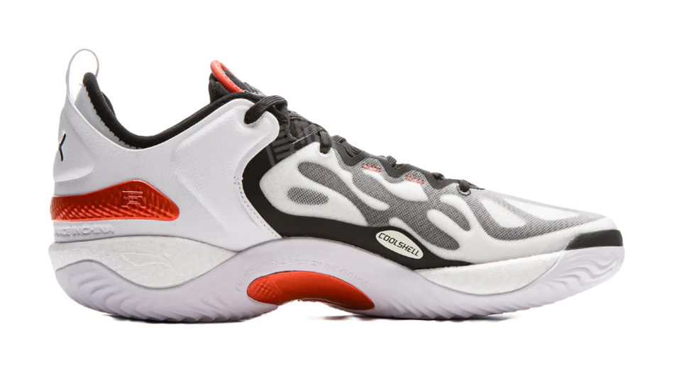White low basketball shoe with black detailing, orange heel panel, lace-up