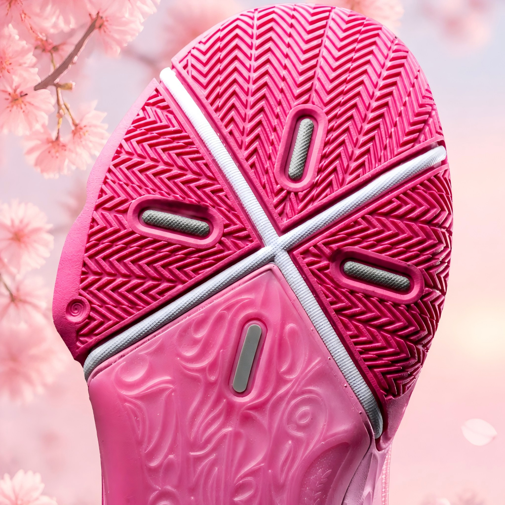 Pink basketball shoe outsole with zigzag tread and molded traction pods.