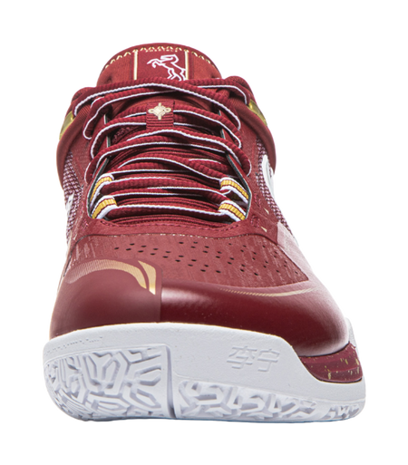 Red badminton shoe toe view with perforated forefoot, striped laces, and white outsole.